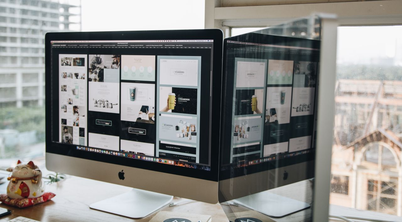 hero-img Dual monitors on a desk, showcasing web design in a modern office setting.